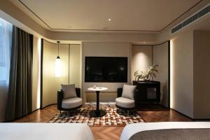 a living room with a table and chairs and a tv at Neyar Luxury and Tranquil Aesthetics Hotel-Prime Location,8-min Walk to Chunxi Road & Sino-Ocean Taikoo Li in Chengdu +65 photos