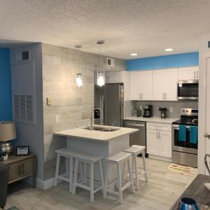 a kitchen with white cabinets and a island with stools at Villa del Sol Condo,inum in Kissimmee