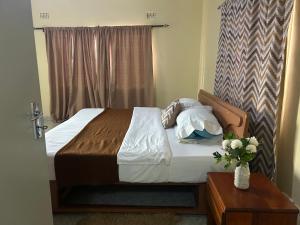 a bed in a bedroom with a vase of flowers on a table at MableHomestay in Mzuzu