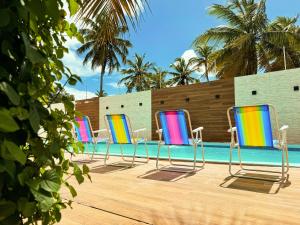 a row of colorful chairs by a swimming pool at Casa Quebec - Apartamentos in São Miguel do Gostoso