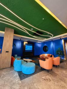 ein Wohnzimmer mit blauen Wänden und orangefarbenen Stühlen und Tischen in der Unterkunft Axis Hotel in Cimenli