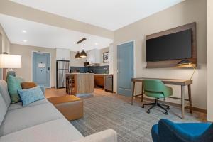 a living room with a couch and a desk with a television at Drury Inn & Suites Destin Miramar Beach in Destin