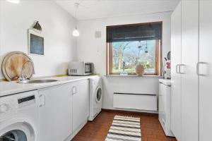 a white kitchen with a sink and a washing machine at FY175-Asperup-Sommerlandsvej-4 in Asperup
