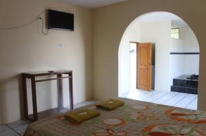 a bedroom with a bed and a tv on the wall at Hostal El Bosque in Pedernales