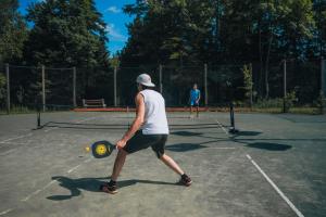 two people playing tennis on a tennis court at Fiddler Lake 72 with Private spa, pool table & Pool in Mille-Isles