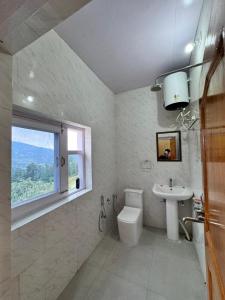 a bathroom with a sink and a toilet and a window at Seraahi Hills Resort in Bhadarwāh