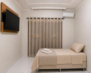 a bedroom with a bed and a flat screen tv at Pousada Economia in Paracatu