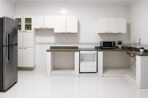 a kitchen with white cabinets and a stainless steel refrigerator at Pousada Economia in Paracatu