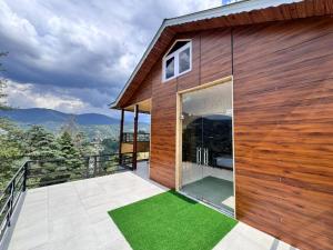 a wooden house with a balcony with green grass at Seraahi Hills Resort in Bhadarwāh