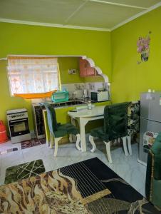 a kitchen with green walls and a table and chairs at ADONAI Homes in Malindi