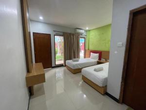a hotel room with two beds and a window at Melati Hotel central kuta mandalika in Kuta Lombok