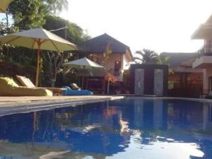 a swimming pool with an umbrella and some chairs at Melati Hotel central kuta mandalika in Kuta Lombok +3 photos