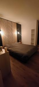 a bedroom with a large bed with a wooden wall at OasisNoir in Calonne-Ricouart