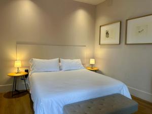 a bedroom with a large white bed with two lamps at Apartamentos Centro in Albacete