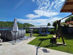 a patio with a pool and an umbrella and a swing at Vikendica Twins in Donji Vakuf