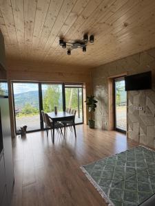 a dining room with a table and chairs and windows at Evergreen cottage in Slavske