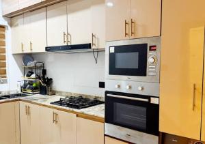 a kitchen with a stove and a microwave at Mega Luxury Apartment in Asagba