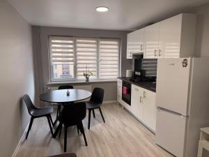 a kitchen with a table and chairs and a refrigerator at Apartment Ventos 55 in Mažeikiai