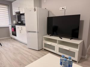 a kitchen with a television and a white refrigerator at Apartment Ventos 55 in Mažeikiai