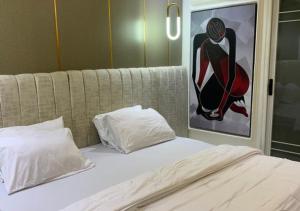 a bed with two pillows and a painting on the wall at Mega Luxury Apartment in Asagba
