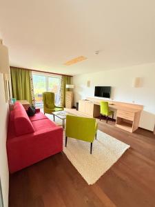 a living room with a red couch and green chairs at Hotel Achentalerhof in Achenkirch