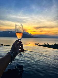 a person holding a glass of wine in front of the ocean at Casa Gaia GuestHouse in Ilhabela