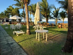 a table with an umbrella and chairs and a table and chairs sidx sidx at Flat 3 Quartos Pé na Areia, Piscina e Mar, Summer House Genipabu, Guarajuba in Guarajuba