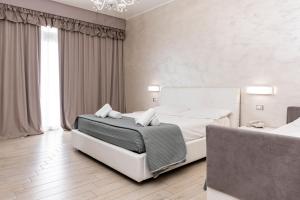 a white bedroom with a bed and a chandelier at Hotel Aurora in Porto Cesareo