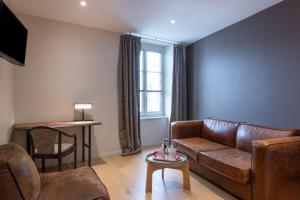 a living room with a leather couch and a table at Hotel Aux Terrasses in Tournus