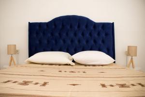 a bed with a blue headboard and two pillows at Jasmin in Gabès +4 photos
