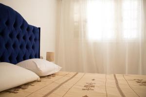 a bedroom with a bed with a blue headboard and a window at Jasmin in Gabès