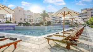 a pool with chairs and umbrellas at a resort at Stunning Sea View Resort Pools Spa Gym Balcony in Paphos