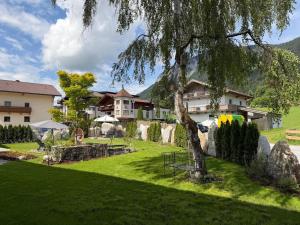 a green yard with a house and a tree at Aparthaus Vergissmeinnicht in Söll