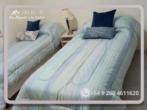 a bedroom with two beds with blue pillows on them at uriburu45 in Malargüe