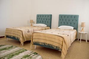 a room with two beds with blue headboards at Jasmin in Gabès
