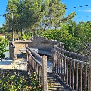 a wooden bridge with a table in a garden at Sunny house in Pierrefeu-du-Var