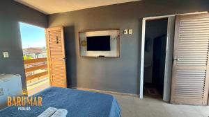 a bedroom with a bed and a flat screen tv at Pousada Barumar in Lucena