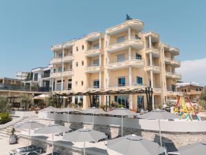 a hotel with tables and umbrellas in front of it at Hotel Blue Moon in Ulcinj