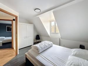 a white bedroom with a bed and a mirror at Gite Loan proche Colmar in Ingersheim