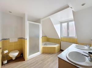 a bathroom with two sinks and a toilet and a tub at Gite Loan proche Colmar in Ingersheim