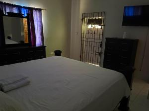 a bedroom with a bed and a dresser and a mirror at Stays at Global Dreams in Beckford Town