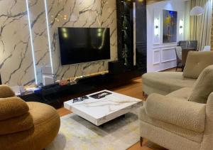 a living room with two chairs and a flat screen tv at Mega Luxury Apartment in Asagba