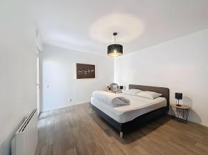 a white bedroom with a bed and a wooden floor at Gite Leny proche Colmar in Ingersheim