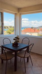 a dining room with a table and chairs and two windows at Apartmani Maria in Preko