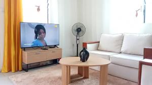 a living room with a white couch and a tv at Côté Plage Kribi Studio Soleil in Kribi
