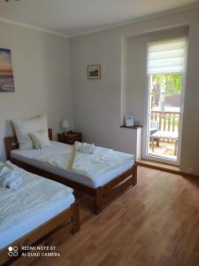 a bedroom with two beds and a window with a patio at Agroturystyka Pod Czaplami in Pieniężno
