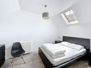 a white bedroom with a bed and a chair at Gite Donald proche Colmar in Ingersheim