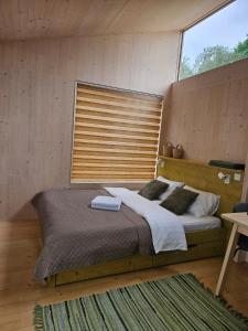 a bedroom with a large bed with a wooden headboard at Piestātne Riverside Cabins with Sauna, Hot Tub & Private Pier in Katlakalns