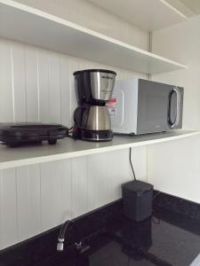 a microwave sitting on a shelf in a kitchen at Cantinho Charmoso Pertinho do Mar in Navegantes