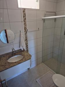 a bathroom with a sink and a mirror and a shower at Pousada Canto da Praça in Bertioga +82 photos